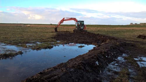 Machine digging low level banks of peat