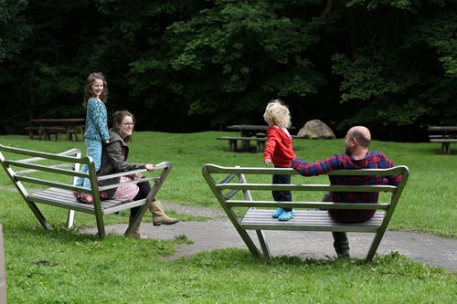 Teulu yn eistedd ar fainc yng Nghwm Clywedog