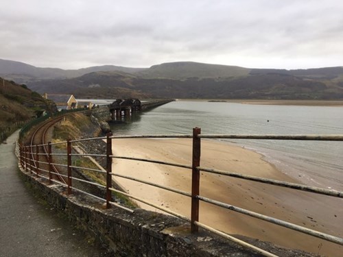 Delwedd o aber Mawddach gyda'r bont reilffordd ar draws o Barmouth i Fairbourne. Mae'r ddelwedd yn dangos pa mor agos yw'r traciau trên i ymyl yr arfordir yn yr ardal hon