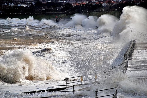 Ymchwydd storm arfordirol ym Mae Colwyn gydag amddiffynfeydd arfordirol i'w gweld.